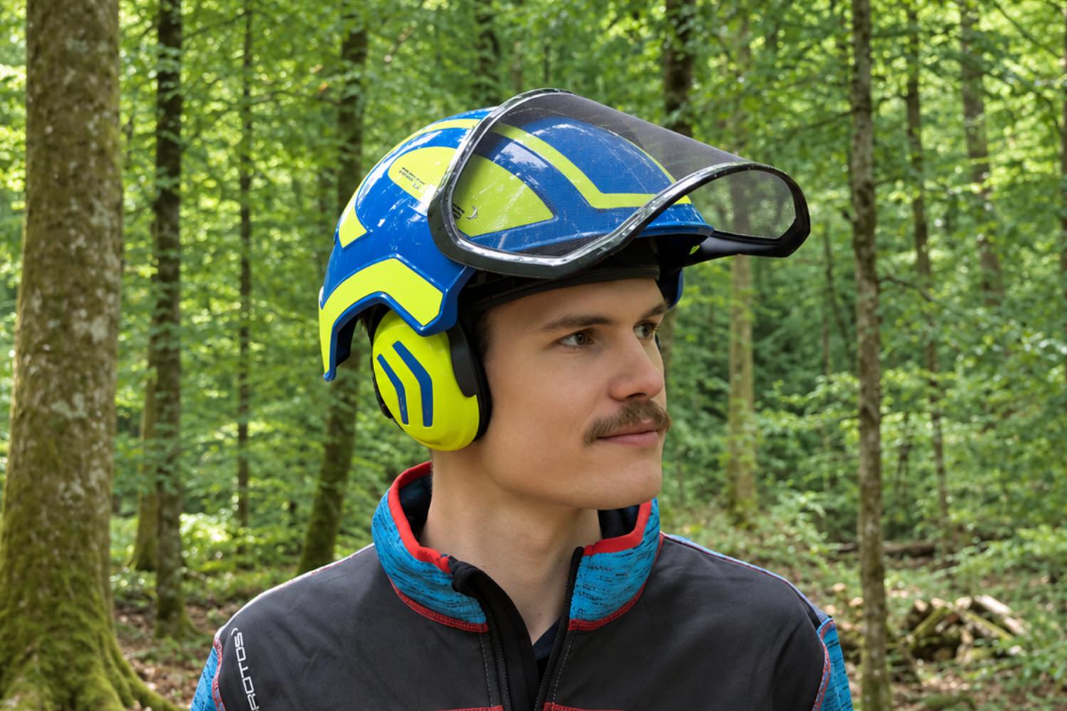 Casque Protos bleu avec visière et protections auditives en forêt